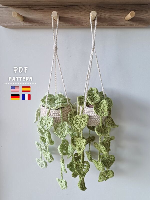 Two crocheted hanging planters with long, cascading heart-shaped leaves suspended from wooden pegs