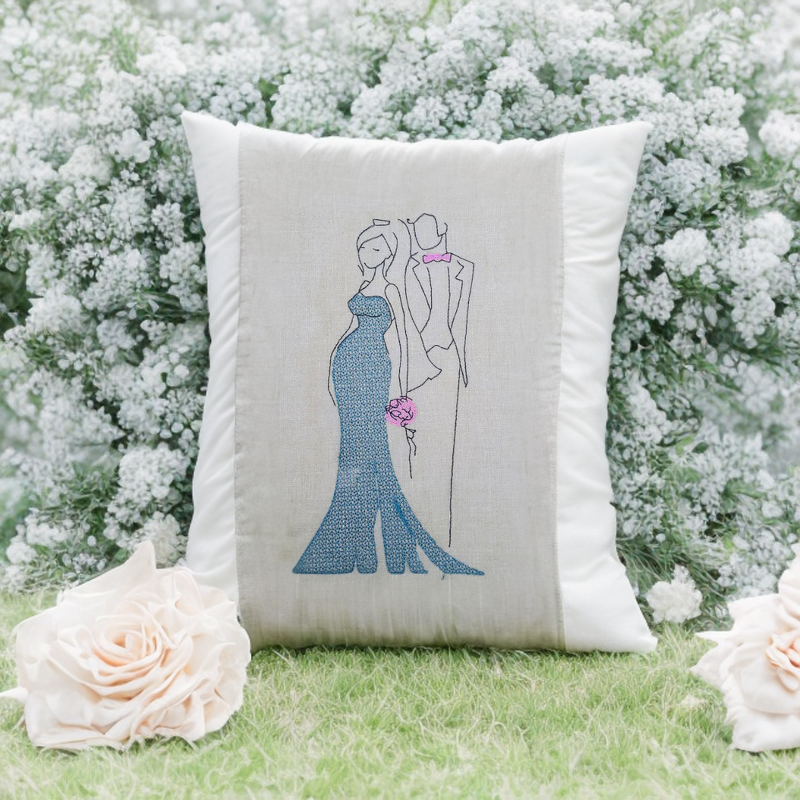 Kissen mit minimalistischer Stickerei eines Brautpaares, blaues Kleid und rosa Blumenakzent