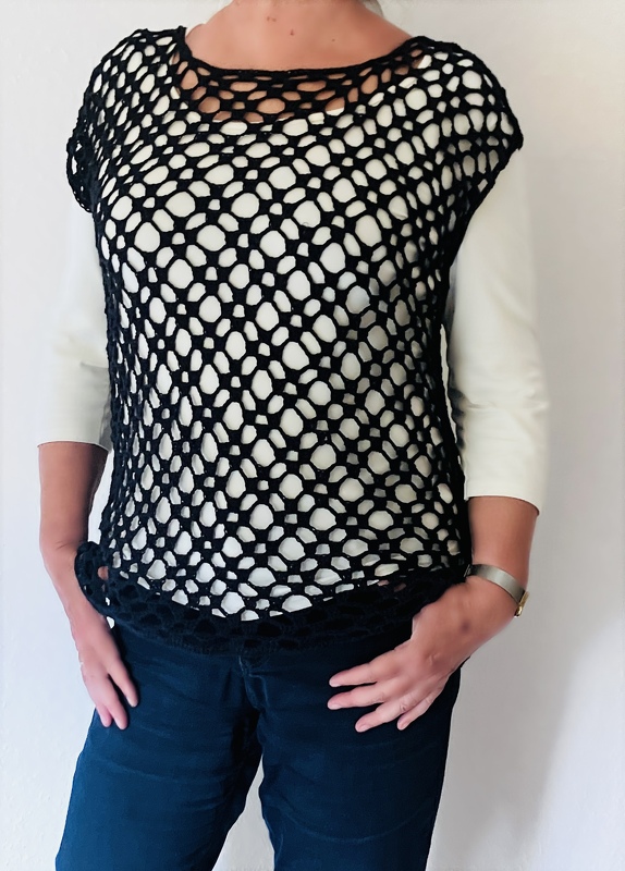 Dame trägt schwarzes gehäkeltes Netz-Top über weißem Unterziehshirt