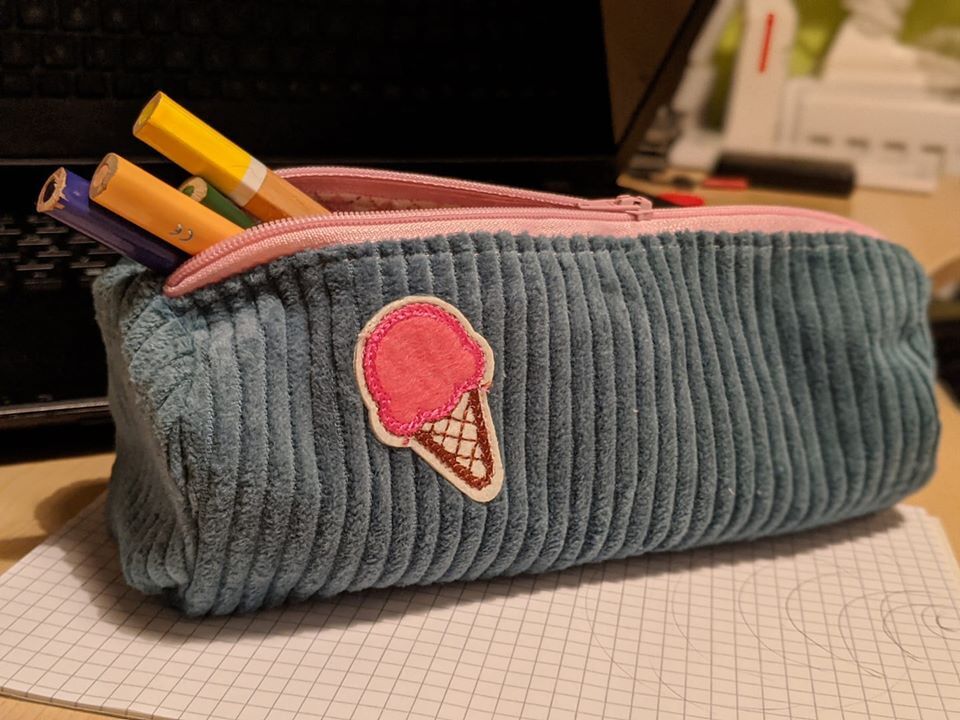 Blaugrünes, geripptes Stiftetui aus Cord mit rosa Reißverschluss und pinker Eiswaffel-Applikation; Buntstifte ragen heraus