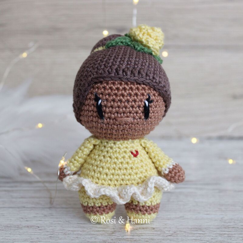 Gehäkelte Amigurumi-Puppe mit gelbem Rüschenkleid und braunem Dutt