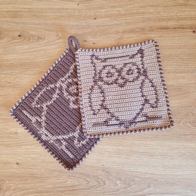 Zwei gehäkelte Topflappen mit Eulenmotiv in Braun und Beige auf Holz