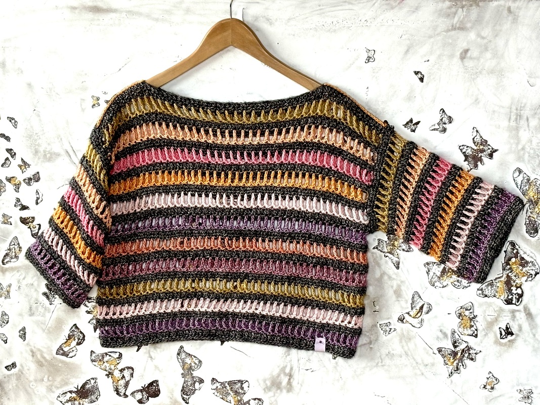 Gehäkeltes kurz geschnittenes Damen-Shirt mit bunten Querstreifen auf Holzbügel