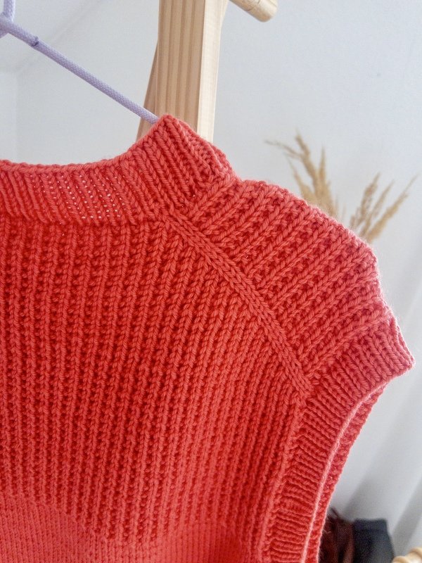 Korallenfarbenes gestricktes ärmelloses Damen-Top mit Rippmuster und Raglannaht an einem Kleiderbügel