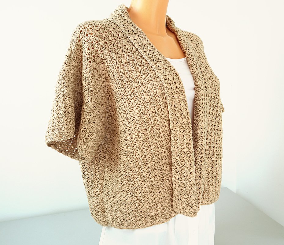 Beige crocheted open-front jacket with shawl collar on a mannequin