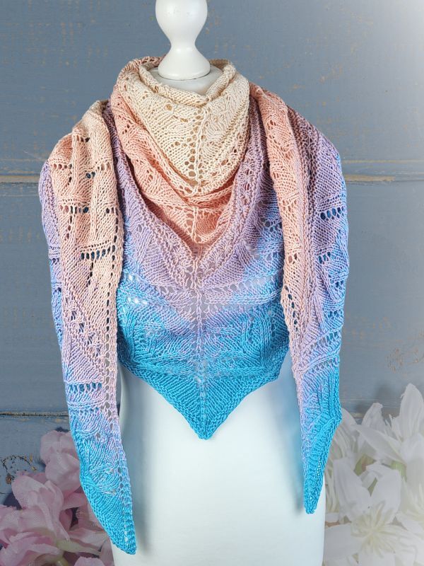 Gestricktes Dreieckstuch in Pastellfarben (Creme, Rosa, Flieder, Türkis) mit Ajourmuster auf weißer Schaufensterpuppe