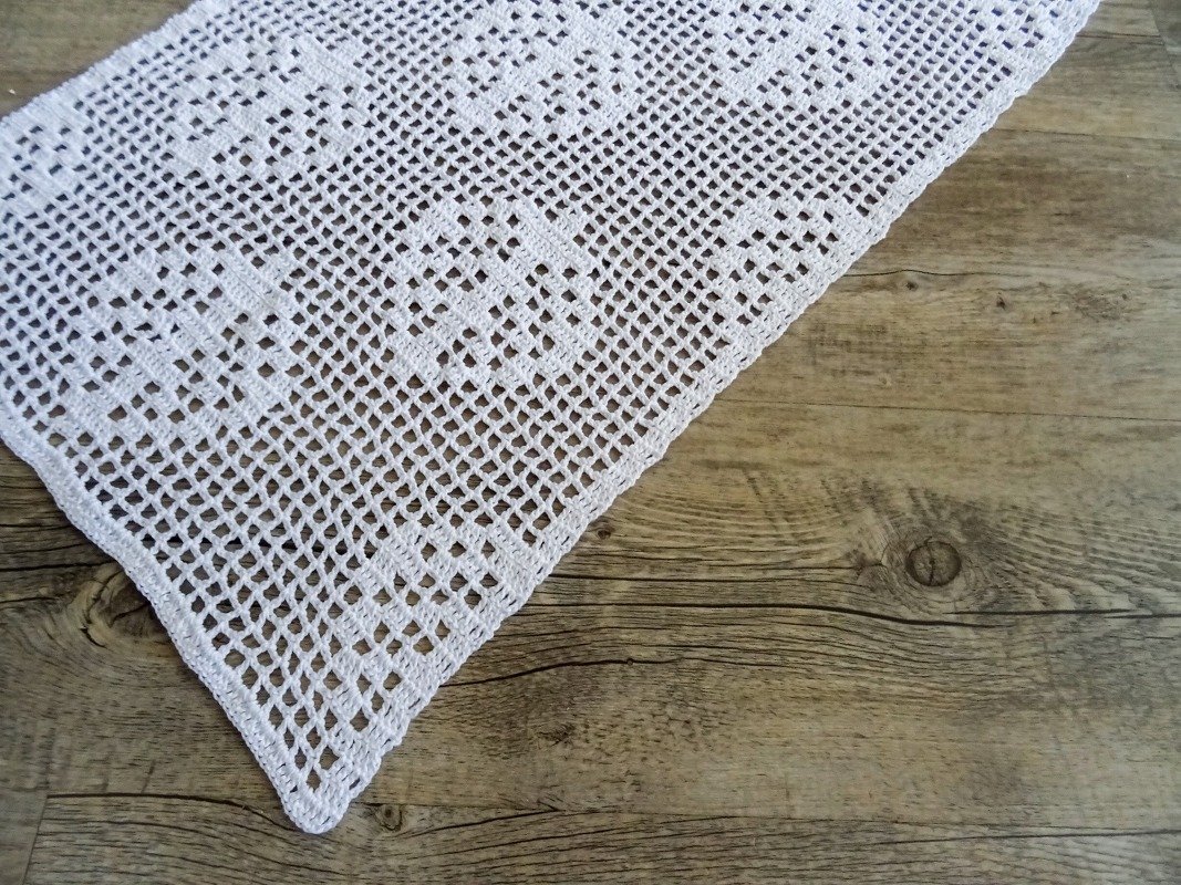 Weißer gehäkelter Filet-Tischläufer auf Holzoberfläche