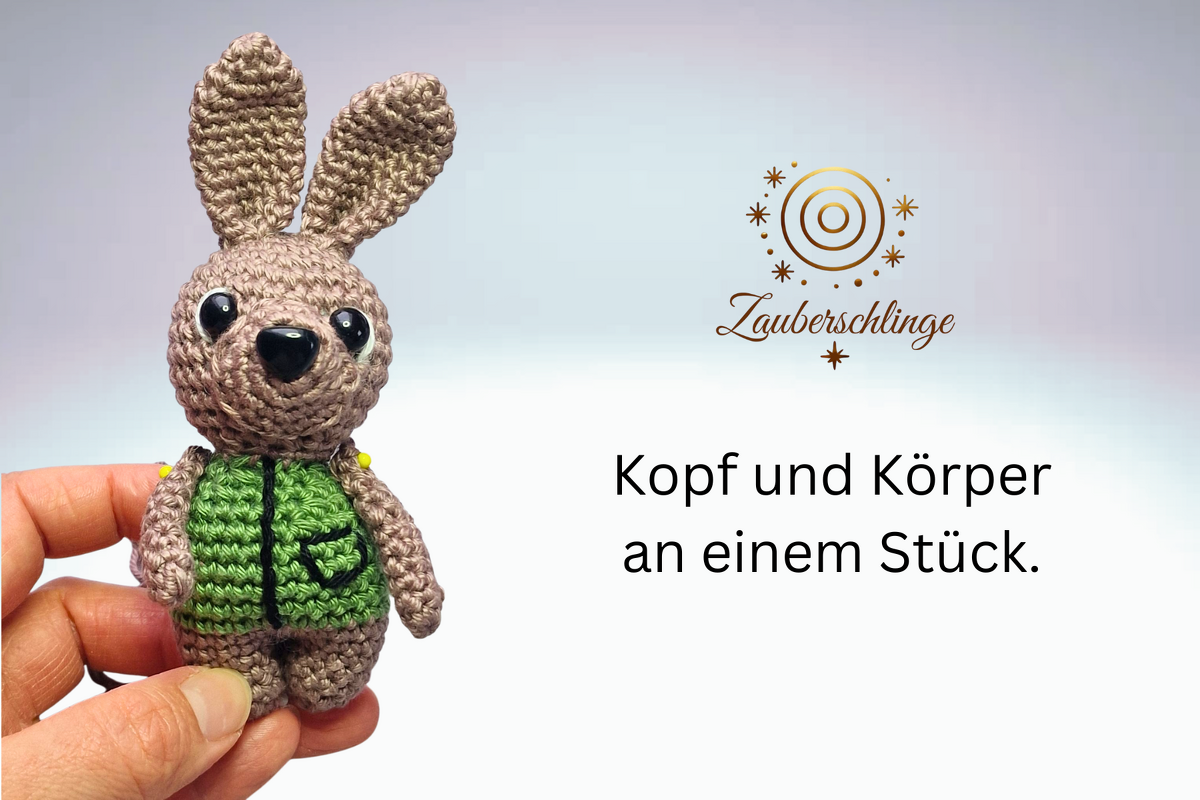 Nahaufnahme eines braunen Amigurumi-Hasen mit grüner Weste, in einer Hand gehalten