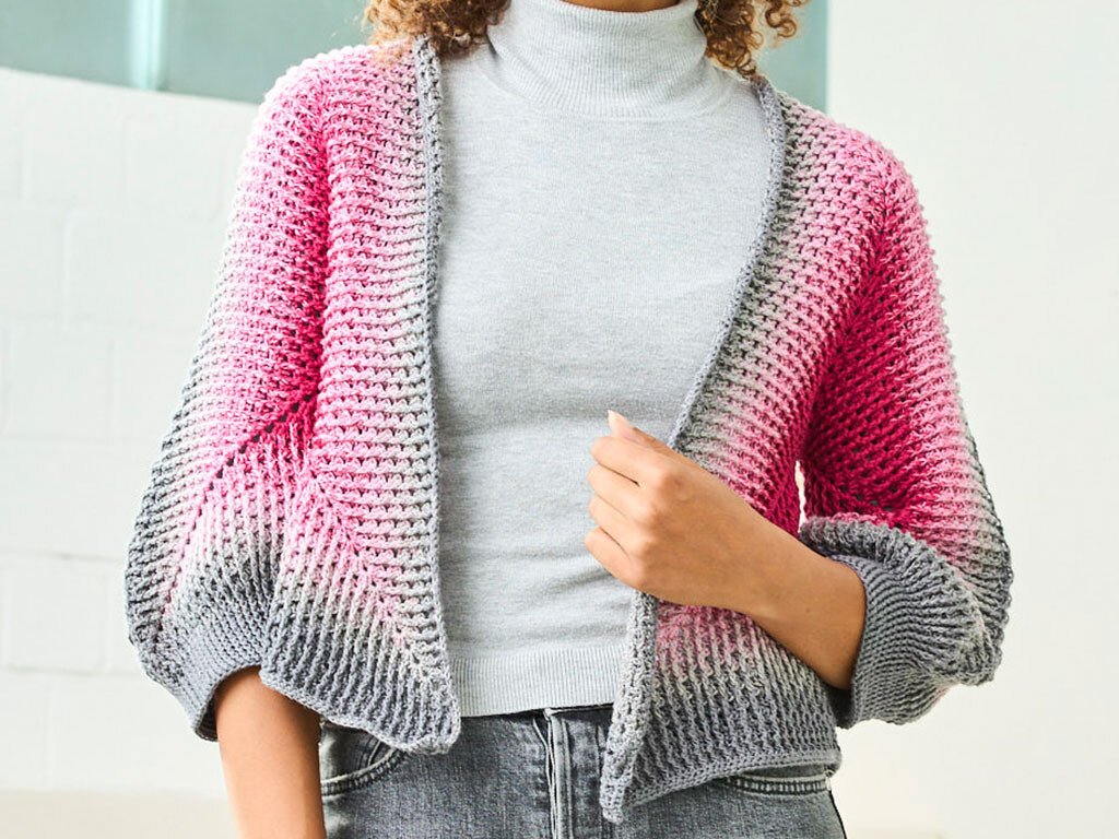 Gehäkelte kurze Damenjacke mit Farbverlauf von Grau zu Pink, offen getragen