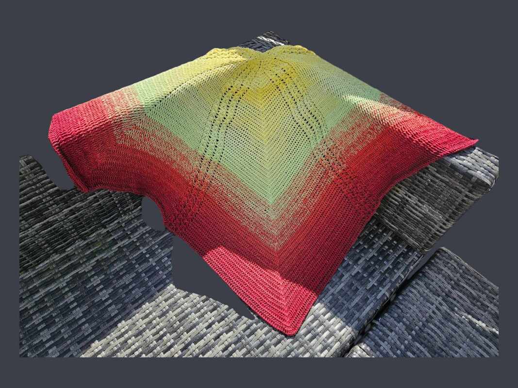 Gehäkeltes Dreieckstuch in Gelb, Hellgrün und Rot mit Lochmuster auf grauem Geflecht.