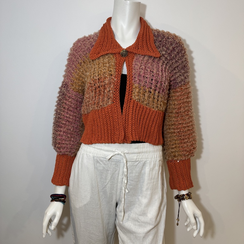 Cropped open-front crochet cardigan with orange, pink and brown patchwork panels on a mannequin.