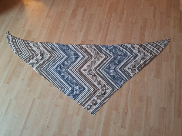 Gestricktes dreieckiges Tuch mit Zickzack- und Streifenmuster in Blau, Braun und Weiß auf Holzfußboden