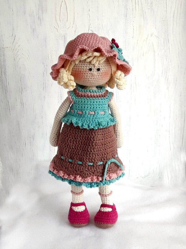 Frontalansicht einer Amigurumi-Puppe mit Glockenhut, mehrlagigem Kleid und pinkfarbenen Schuhen