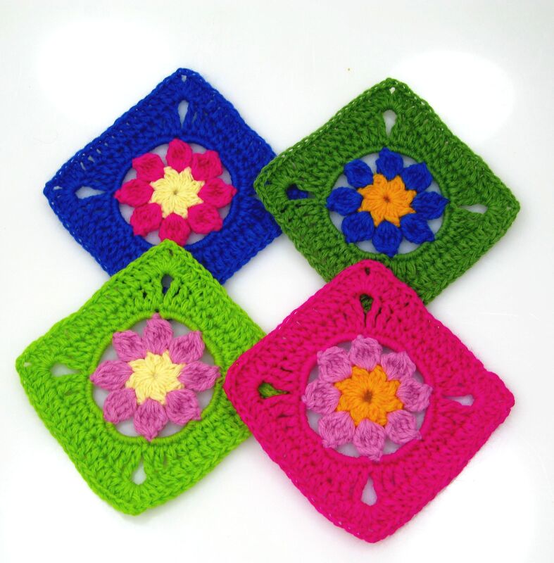 Vier bunte gehäkelte Granny Squares mit blühendem Zentrum