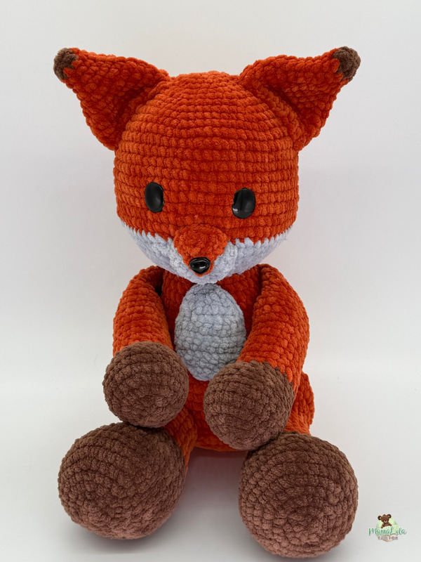 Sitzender Amigurumi-Fuchs in Orange mit braunen Pfoten, hellgrauem Bauch und großen schwarzen Augen.