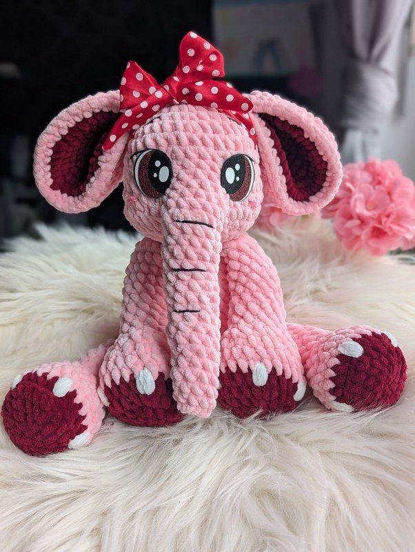 Rosa gehäkelter Amigurumi-Elefant mit roter gepunkteter Schleife