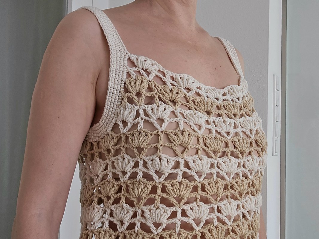 Nahaufnahme eines gehäkelten Damen-Tops mit Muschelmuster in Beige und Creme.