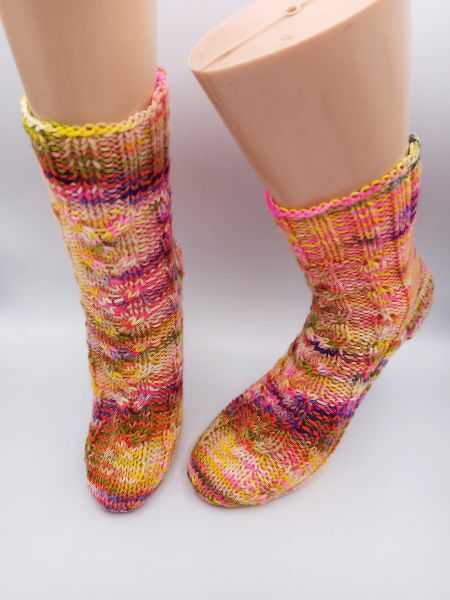 Handgestrickte, mehrfarbige Stricksocken mit geripptem Bündchen auf Schaufensterfüßen
