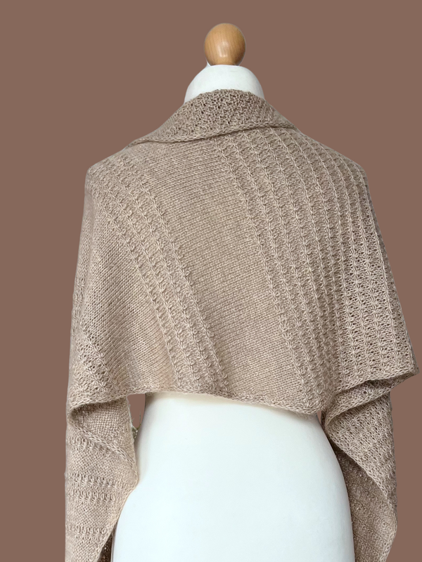 Rückansicht eines beigefarbenen gestrickten Dreieckstuchs mit Rippen- und Lochmuster auf Schneiderpuppe