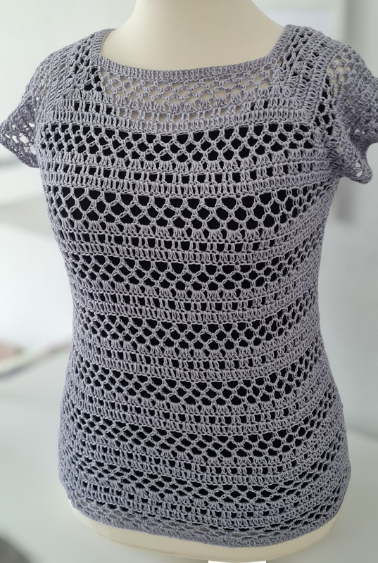 Lavendelfarbener kurzärmeliger Häkelpullover mit Lochmuster auf Schaufensterpuppe, dunkles Untertop sichtbar