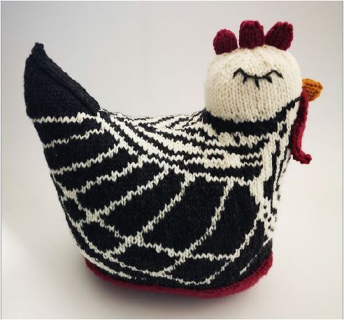 Handgestrickte Henne in Schwarz-Weiß mit rotem Kamm und orangefarbenem Schnabel vor hellem Hintergrund