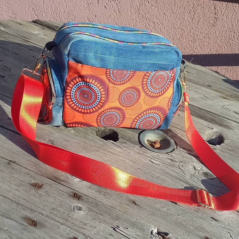 Crosstasche aus Denim mit orangefarbenem Stoffpanel, zwei Reißverschlüssen und rotem, verstellbarem Gurt