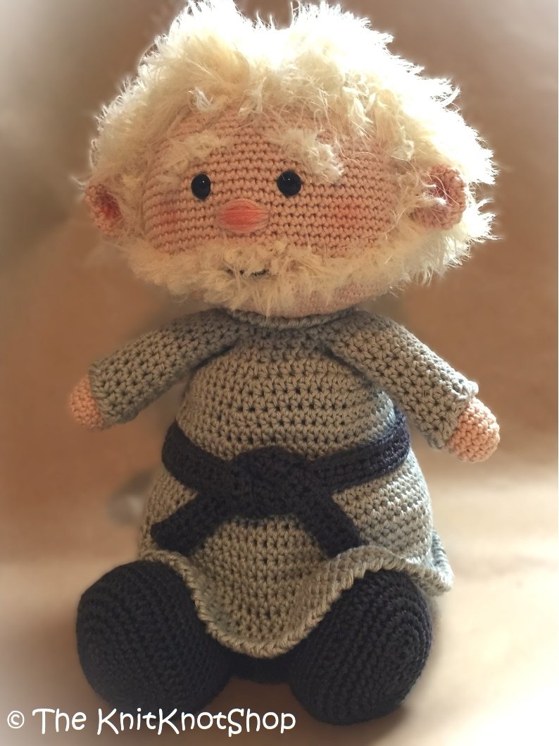 Stehender gehäkelter Wichtel mit rundem Körper, dunklem Gürtel und flauschigem Bart