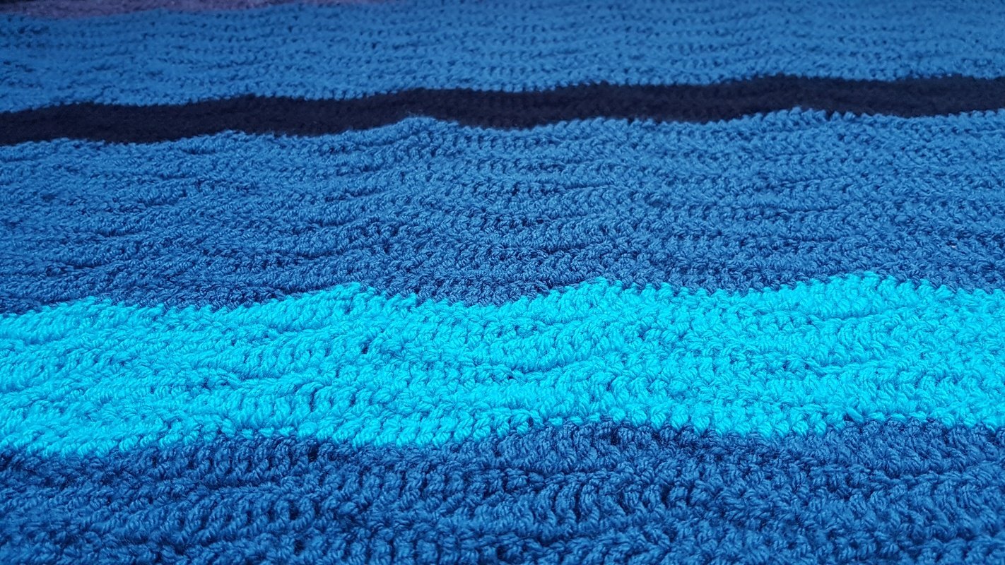 Detail der Maschenstruktur einer blau gestreiften gehäkelten Decke