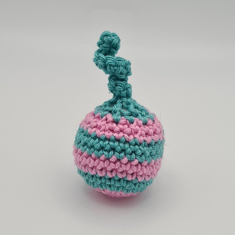 kleine gehäkelte Katzen-Spielkugel mit rosa und türkis gestreiftem Muster und gedrehter Schlaufe oben