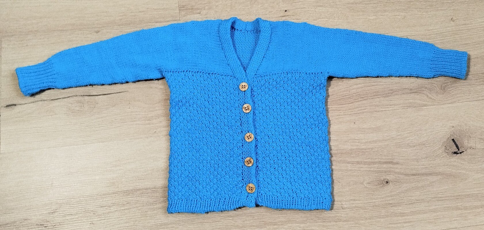 Blaue gestrickte Jacke mit V-Ausschnitt und fünf Holzknöpfen