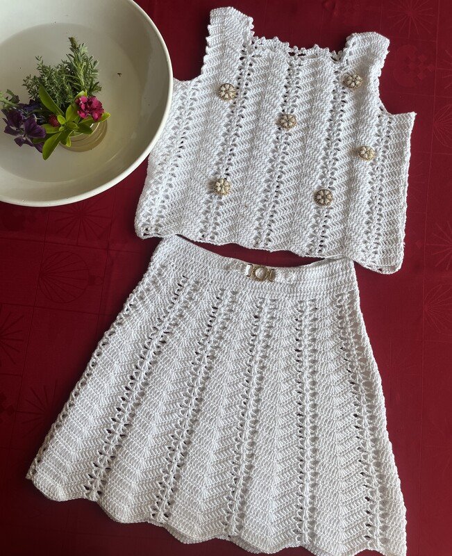 Weißes gehäkeltes Top und passender Rock für Kinder mit Muschel- bzw. Fächermuster und Zierknöpfen.