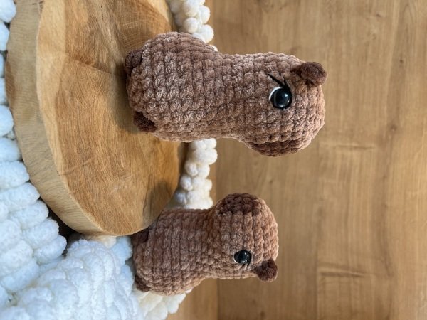 Zwei braune Amigurumi-Tierfiguren aus Chenille-Garn auf Holz mit cremefarbenem Grobstrick
