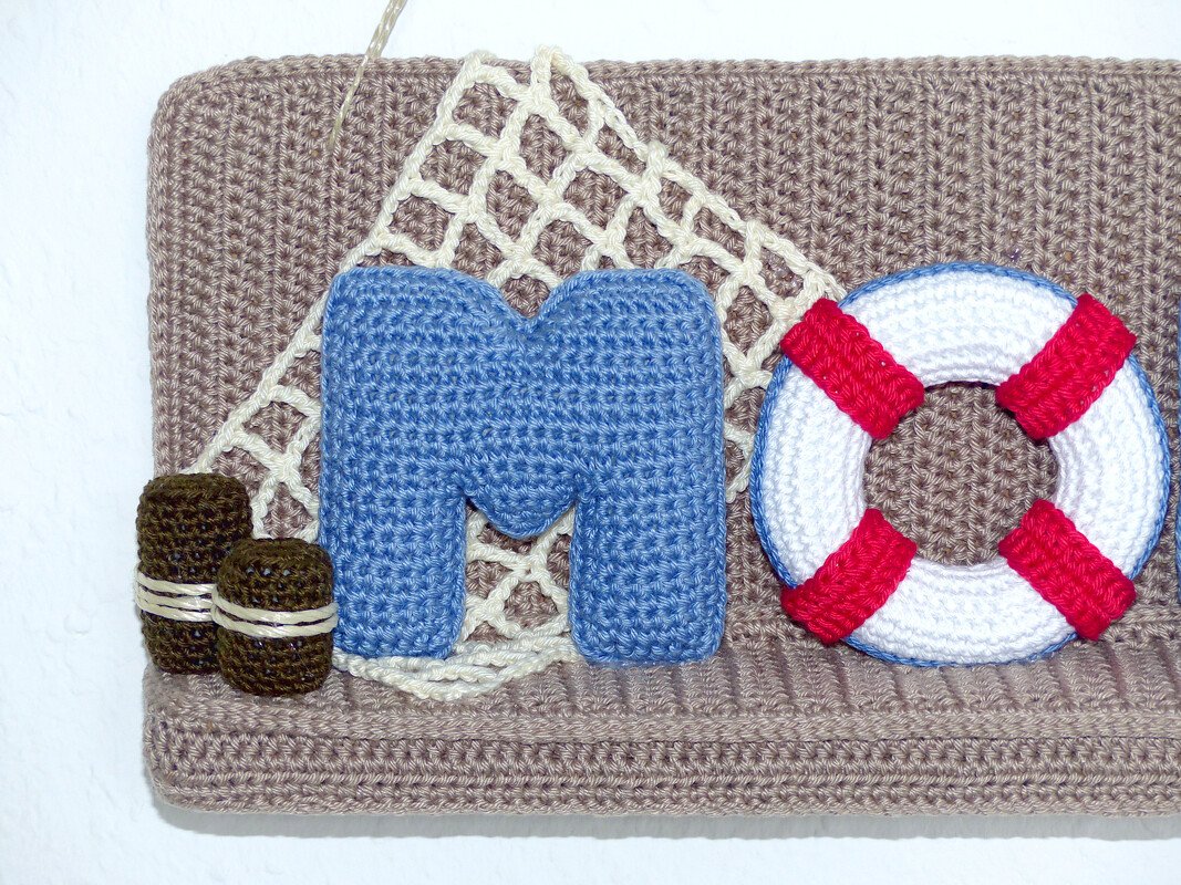 Gehäkelte maritime Wanddekoration mit blauem Buchstaben M und Rettungsring