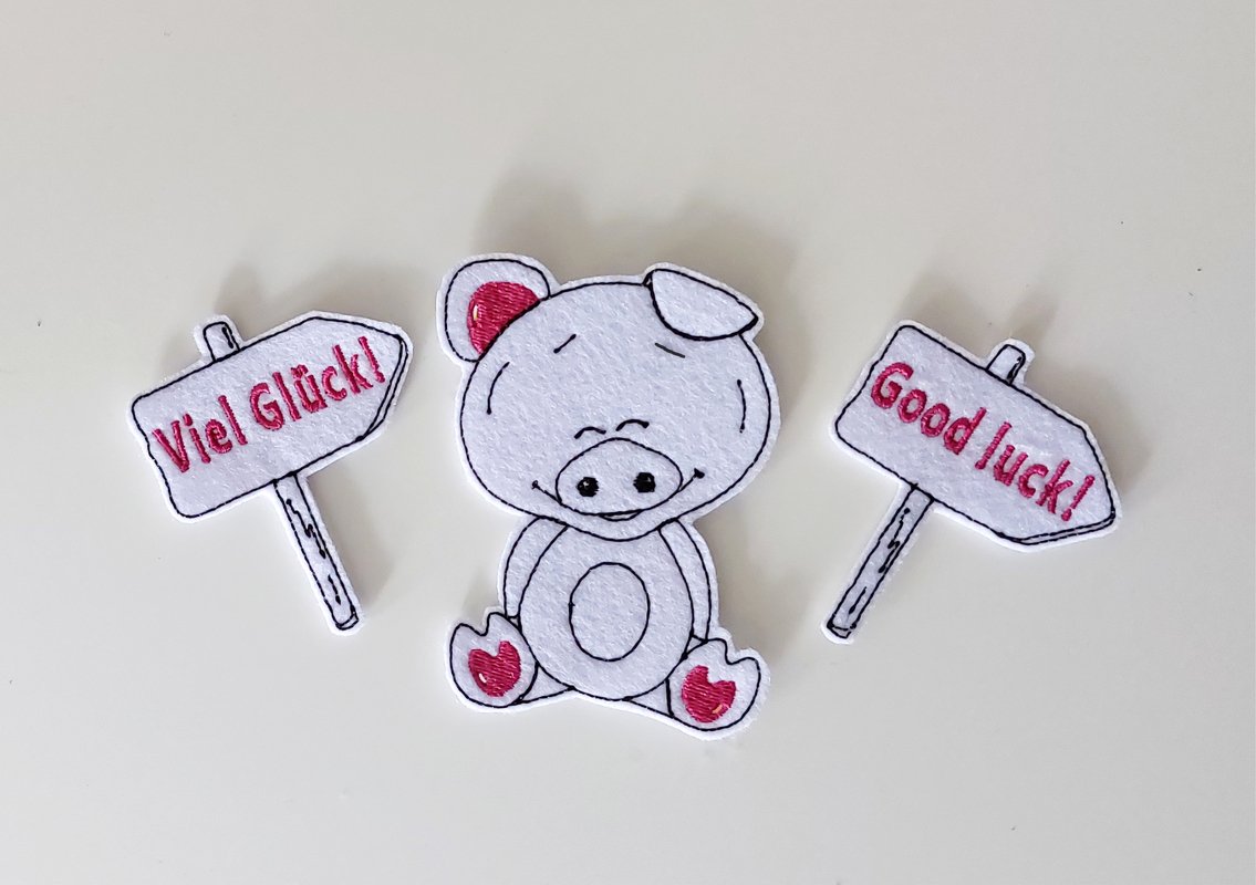 Stickdatei Gl&uuml;cksschweinchen mit Schildern "Viel Gl&uuml;ck" "Good luck"&ndash; 10x10