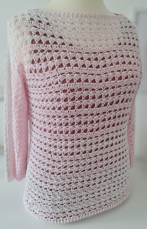 Gehäkelter zartrosa Damenpullover mit Lochmuster auf Schaufensterpuppe