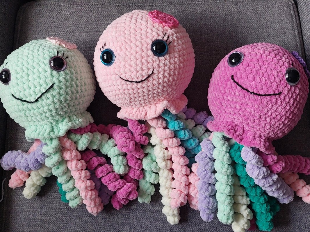 Drei pastellfarbene Amigurumi-Quallen als dekorative, kuschelige Figuren
