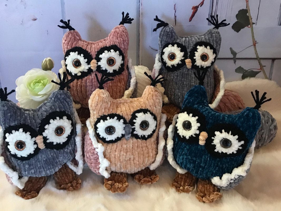 Fünf gehäkelte Amigurumi-Eulen in Pastellfarben mit großen, runden Augen auf hellem, flauschigem Untergrund.