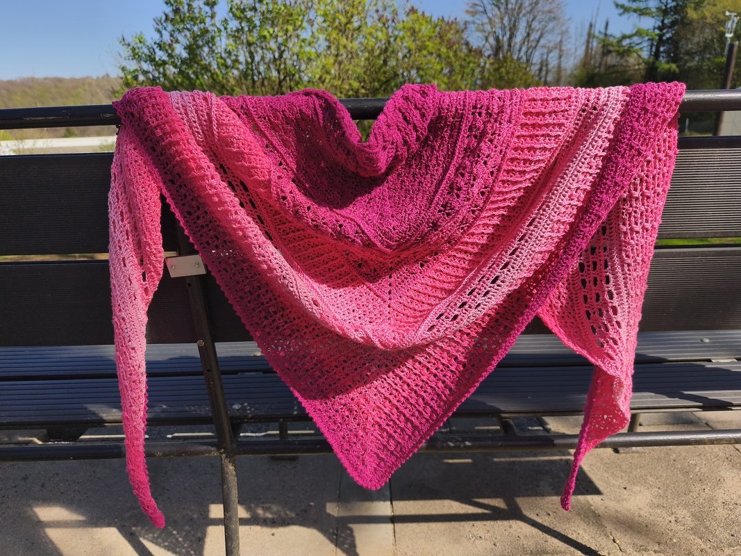Gehäkeltes Dreieckstuch in Pink mit Farbverlauf auf einer Bank