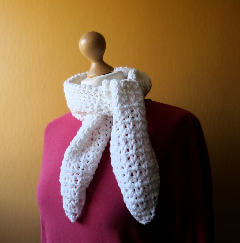 Weißer gehäkelter Schal mit Lochmuster um eine Schaufensterpuppe gelegt