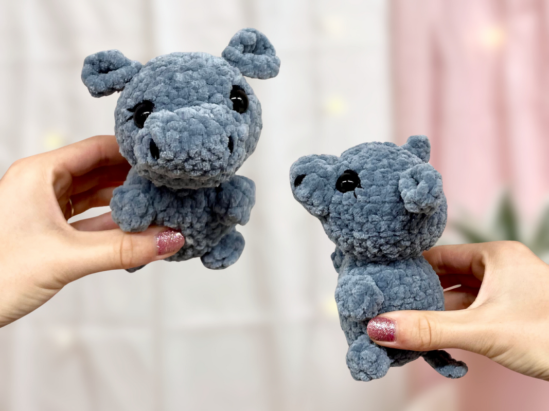 Zwei blaue gehäkelte Nilpferd-Amigurumis, von Händen gehalten