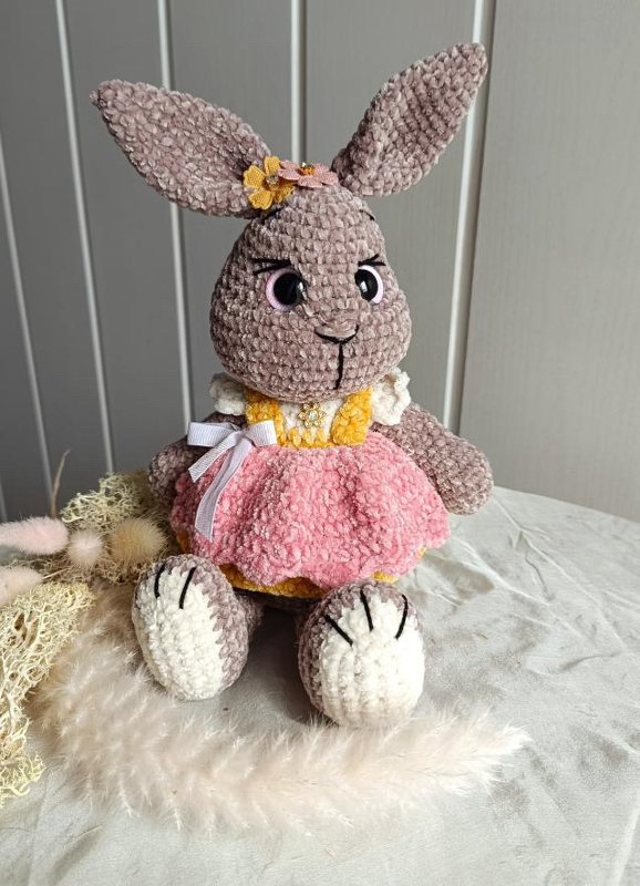 Amigurumi-Häschen mit langen Ohren trägt ein Kleid mit flauschigem rosa Rock und Schleife