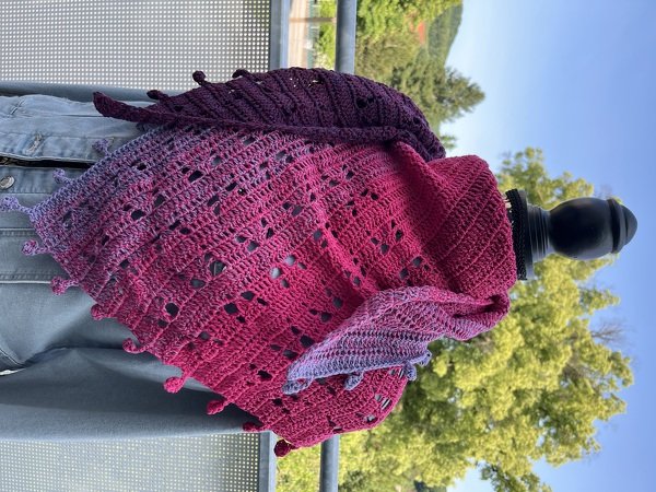 Gehäkeltes Dreieckstuch in Lila-Pink mit Farbverlauf und Lochmuster, an einer Schaufensterpuppe drapiert