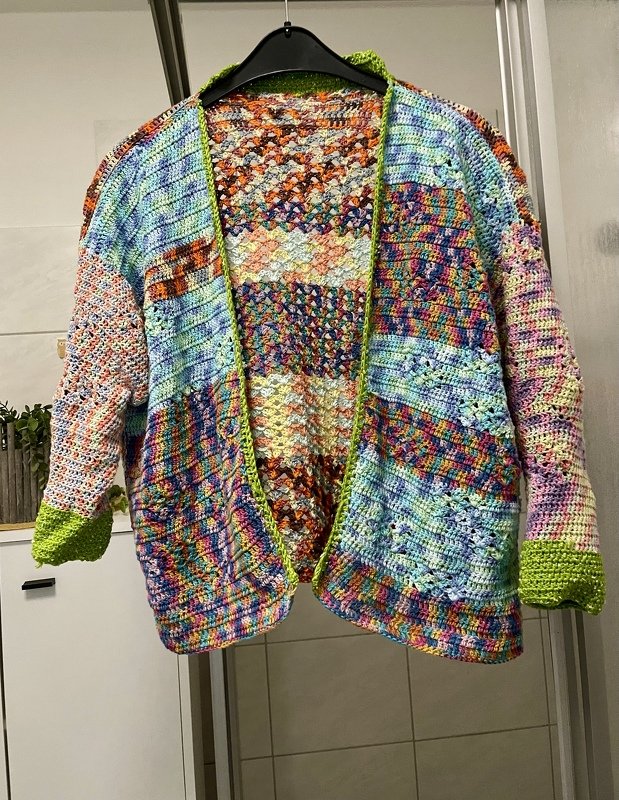 Mehrfarbige Häkeljacke auf Bügel mit grünem Saum