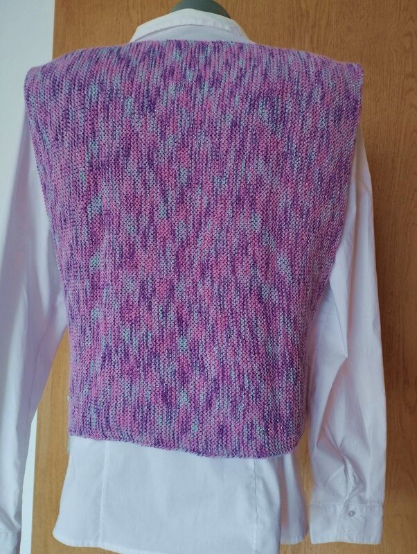 Rückansicht eines gestrickten Pullunders in Lila‑Rosa‑Blautönen über weißem Hemd