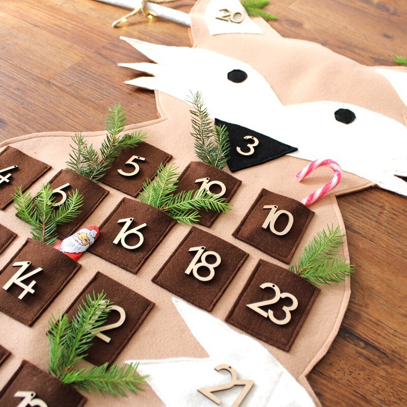 Beiger Filz-Adventskalender in Tierform mit braunen Filztaschen, nummerierten Holz-Zahlen und verschiedenen Füllungen