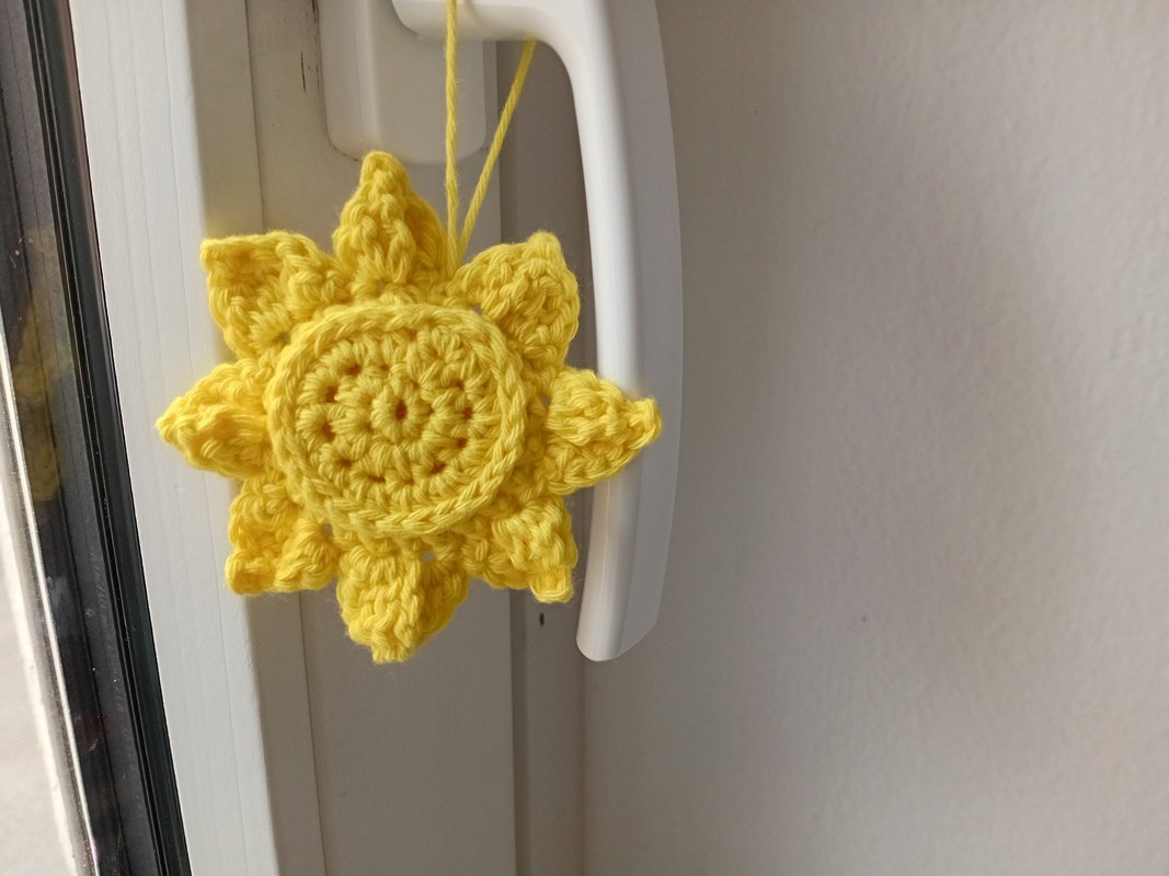 Gehäkelter gelber Sonnenanhänger an weißem Fenstergriff