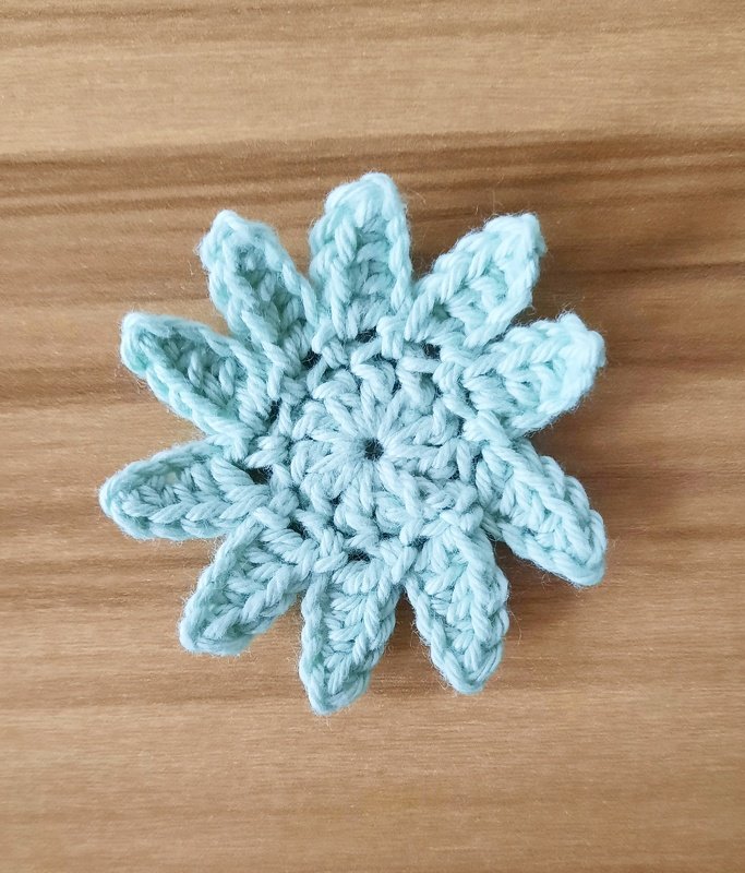 Gehäkelte hellblaue Sternblume auf Holzuntergrund