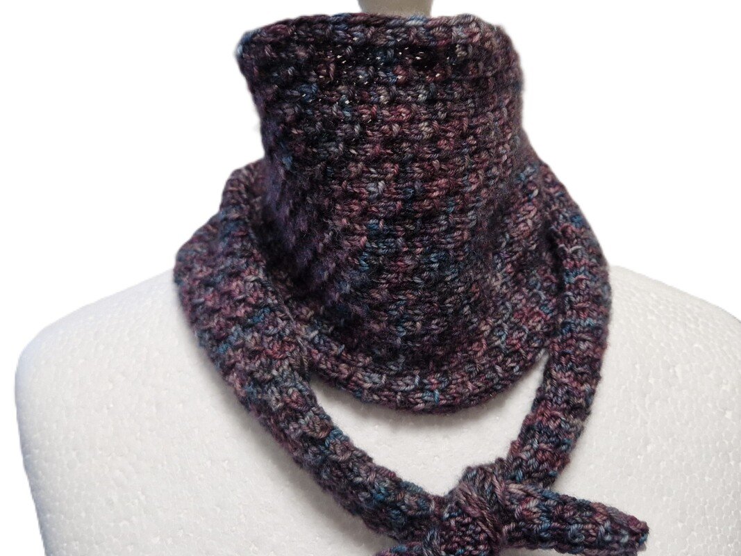 Strickkragen in Melange-Optik (dunkelviolett, blau, rot) mit Bindedetail auf weißer Schaufensterpuppe.