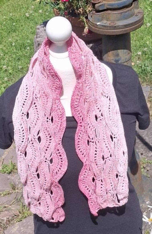 Pink ombr
r
rectangular crochet shawl with shell lace panels and scalloped edges draped on a mannequin.