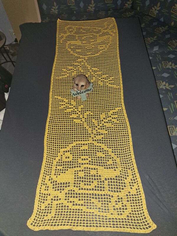 Gehäkelter gelber Filet-Tischläufer mit stilisierten Tier- und Rundmotiven, teils mit kleiner Deko-Figur belegt